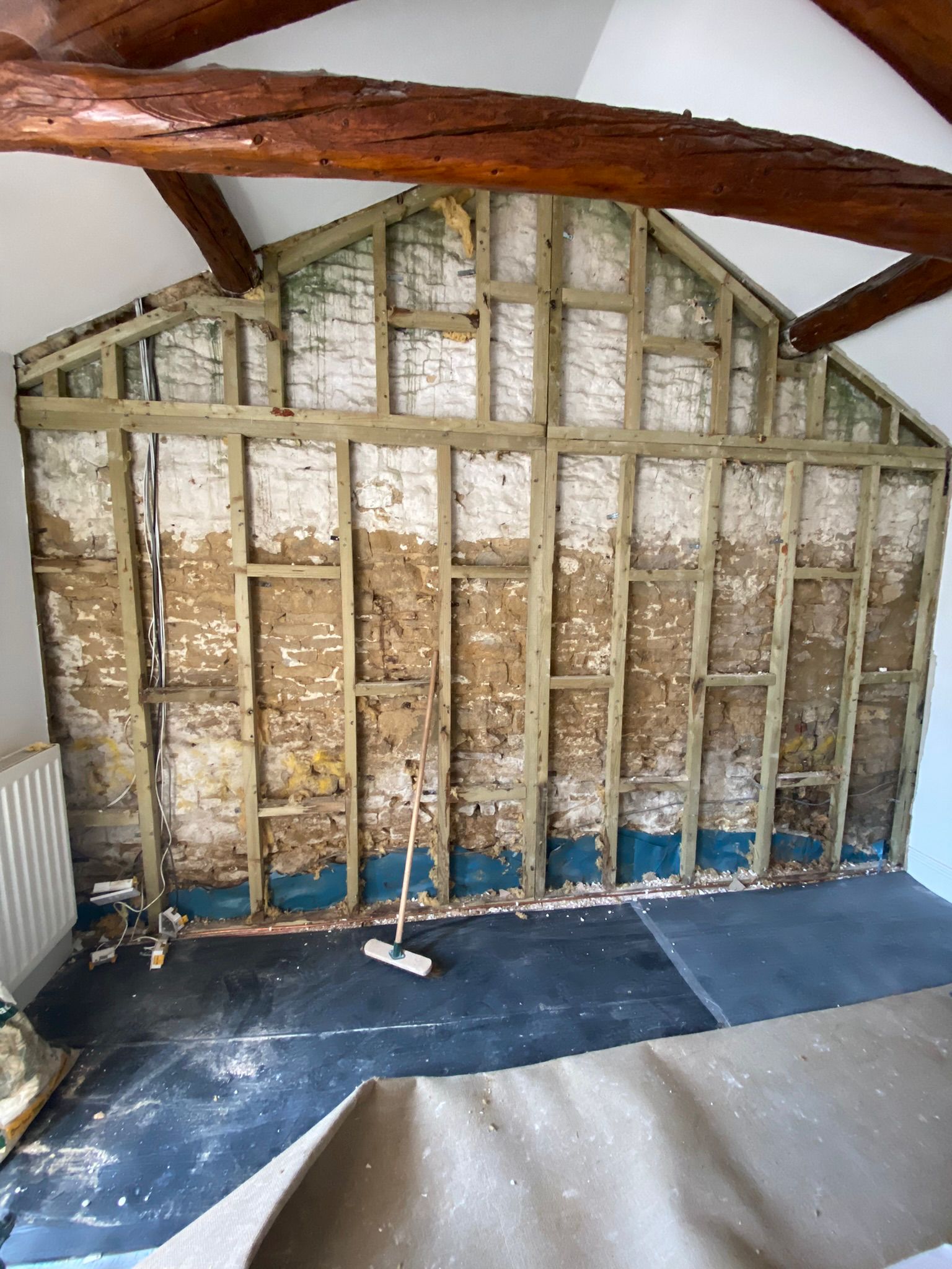 The stripped out gable end wall, showing damp timbers