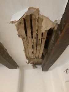 Lath and lime plaster ceiling in 16th century cottage - broken plaster and bare patches showing the laths