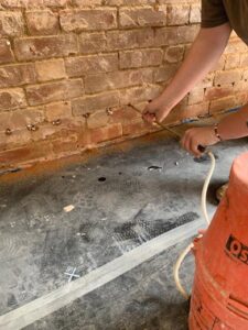 A Property Conservation Services technician, injecting a chemical damp proof course