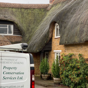 The Property Conservation Services van parked in front of the thatched cottage in Upper Tysoe, needing timber treatment for woodworm infestation.