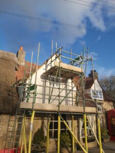 Lime render applied over the horizontal laths, seen through the scaffold