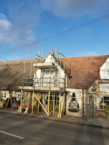 Lime render applied over the horizontal laths, seen through the scaffold