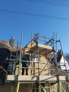 A Property Conservation Services plasterer on the scaffold, applying the lime render over the horizontal laths,