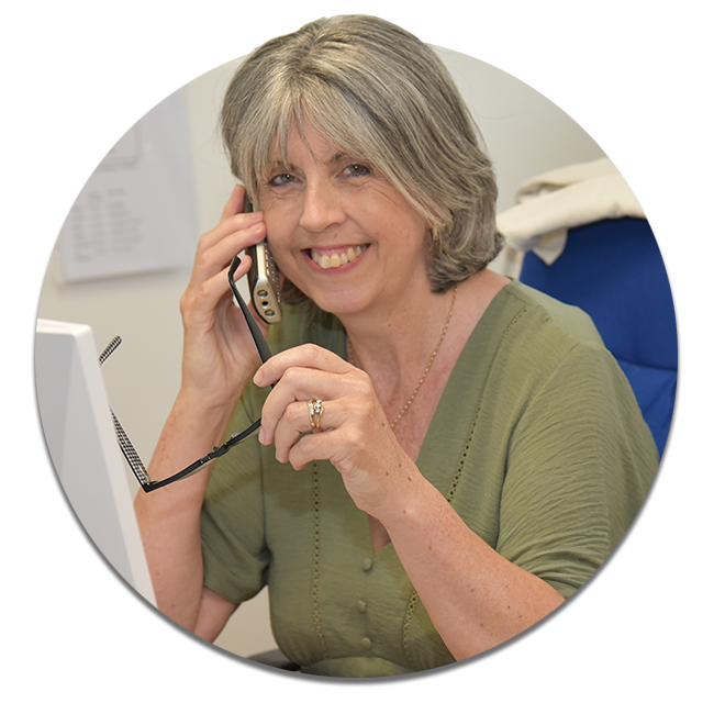 Casual smiling business woman sitting at desk making telephone call and taking note.