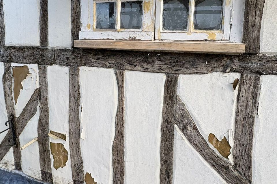 Exterior façade of a listed building where sand and cement render has crumbled off. This was replaced with traditional lime plaster by Property Conservation Services