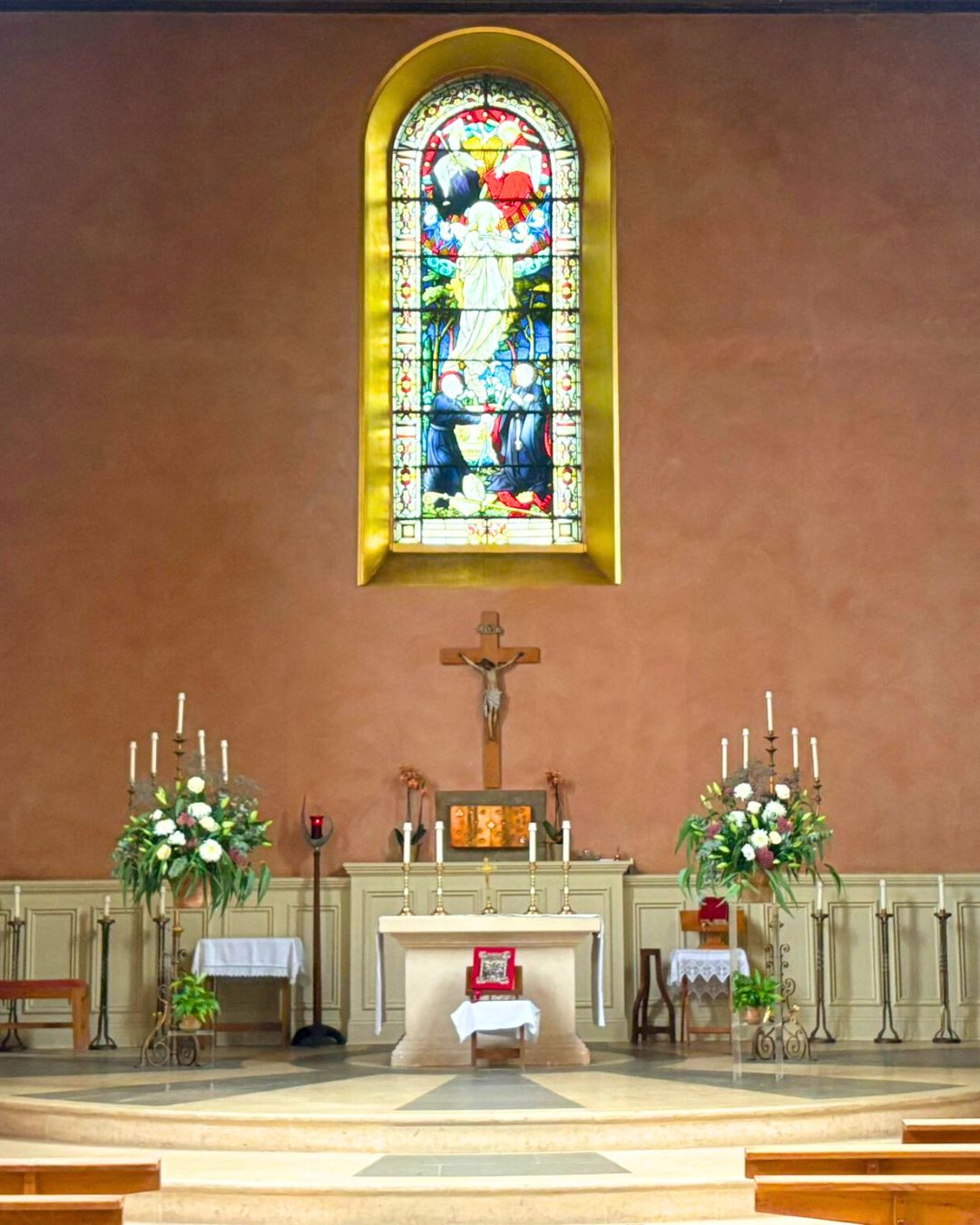 The church alter with a magnificently detailed stained glass window above.