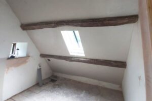 A sloped ceiling with original beams and fresh lime plaster