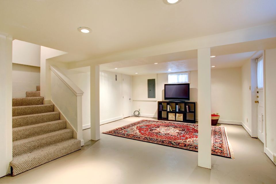 A white and cream basement with carpeted stairs and entertainment set-up
